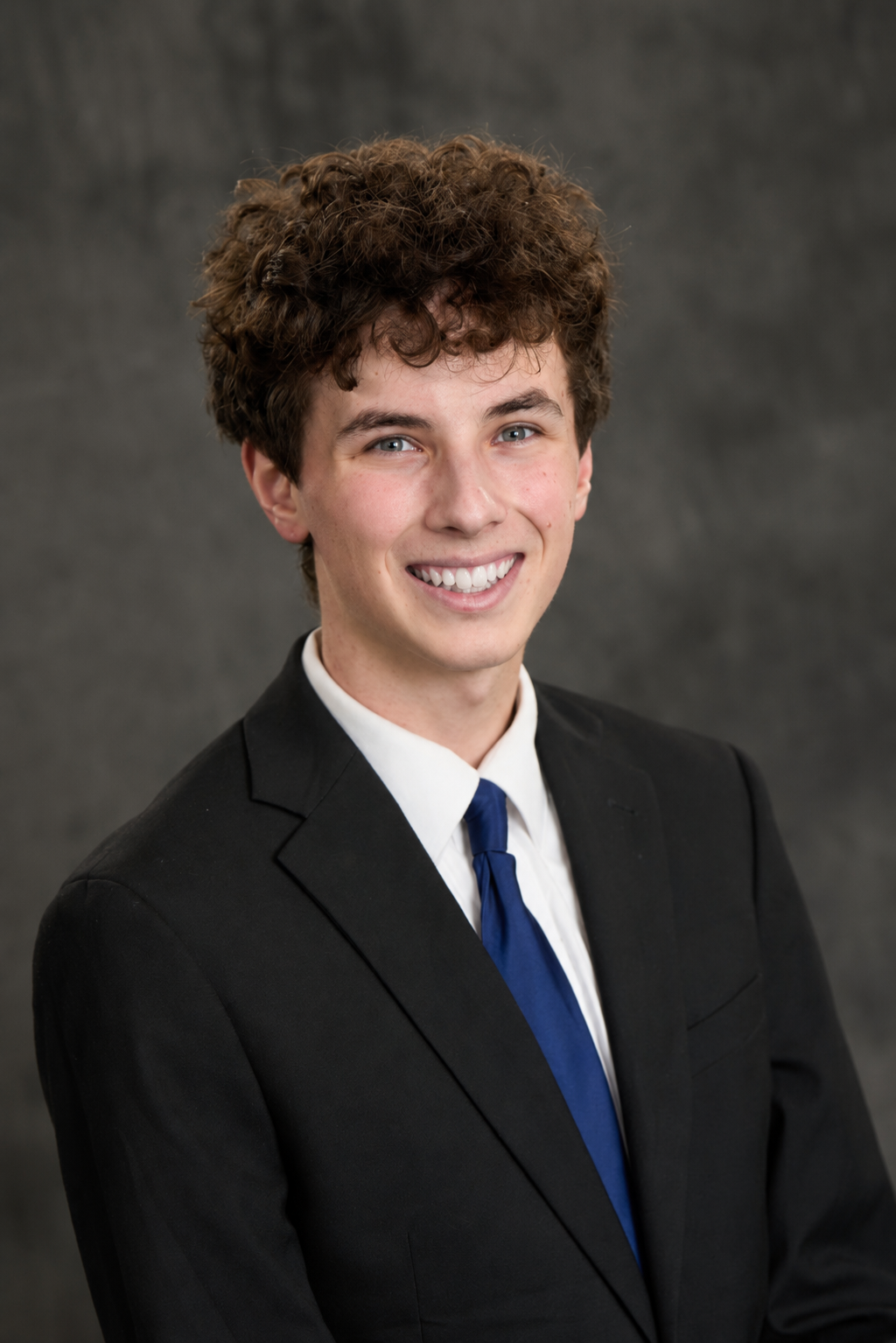 Samuel Roth smiling, wearing a suit and blue tie